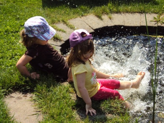 little girl splashing feet in backyard pond 