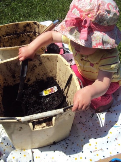 Toddler digging in bucket of mud