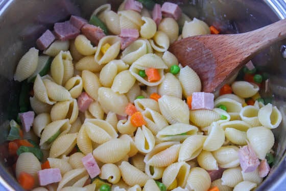 stirring pasta with ham and veg