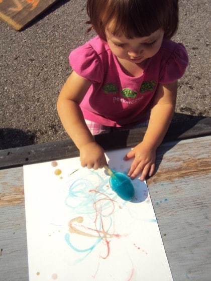 Toddler painting outdoors with ice