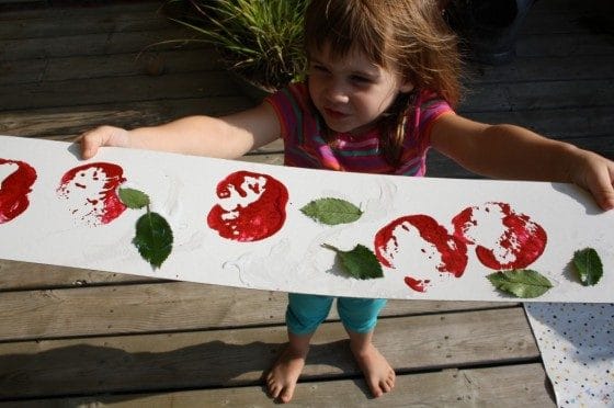 Toddler holding up apple stamping art