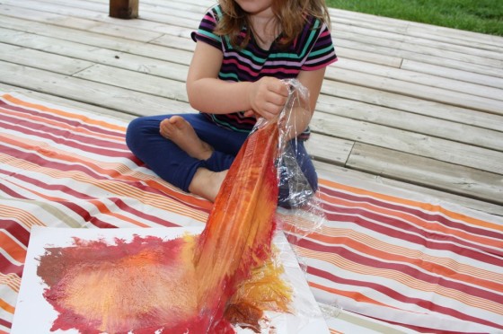toddler pulling plastic wrap off wet paint