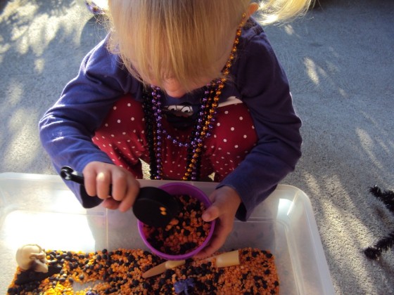 toddler playing with lentils in halloween sensory bin 