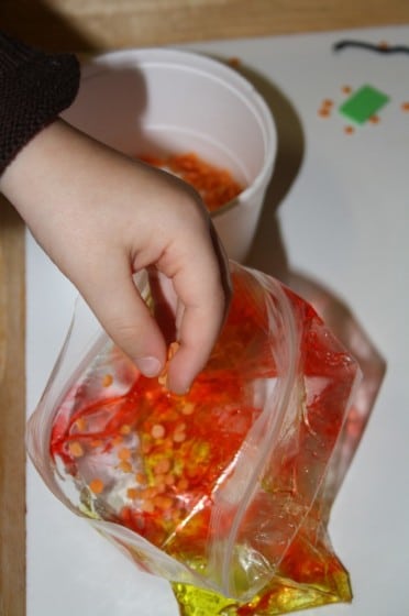 toddler putting lentils and hair gel into sandwich bag