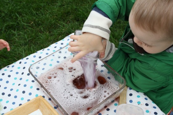 toddler pouring red bubbly water