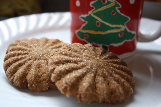 2 baked ginger cookies on plate beside Christmas mug