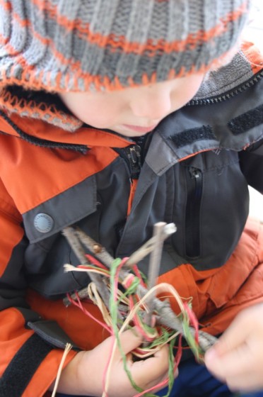 Child wrapping raffia around twig star ornament