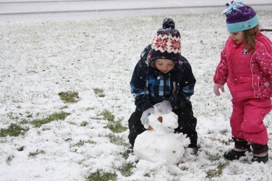 3 year olds building snowman 