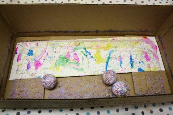 golf balls, paint and paper in cardboard box