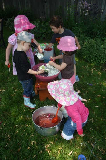 Preschoolers and toddlers cutting flowers into bowls of water during science play