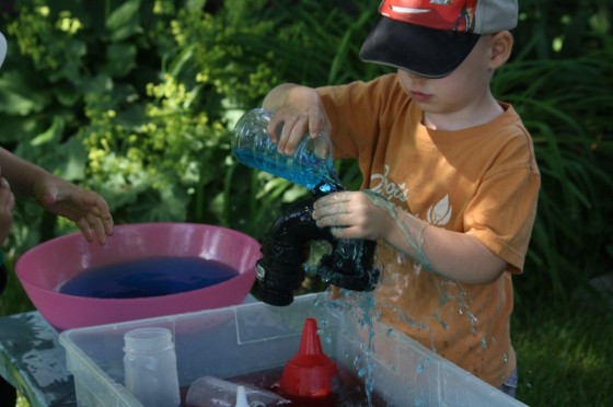 toddler pouring water through funnel during a science activity