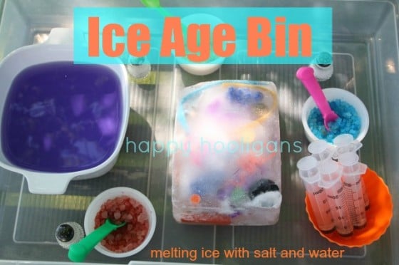 Block of ice with small toys frozen inside, purple water, coloured salt, in plastic bin