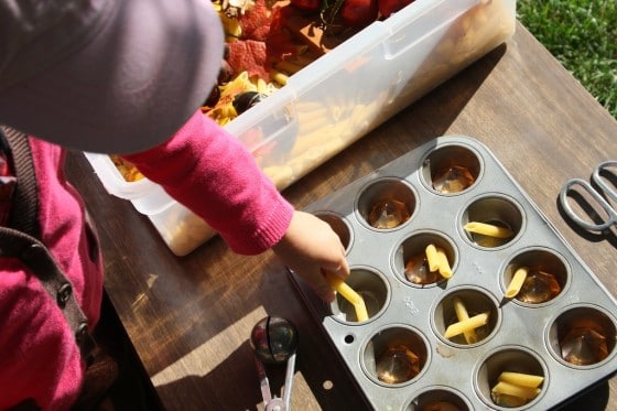 toddler sorting dried pasta in muffin tin