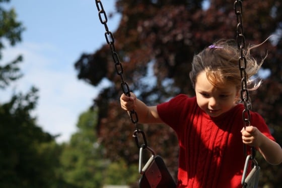 preschooler in red dress on swing