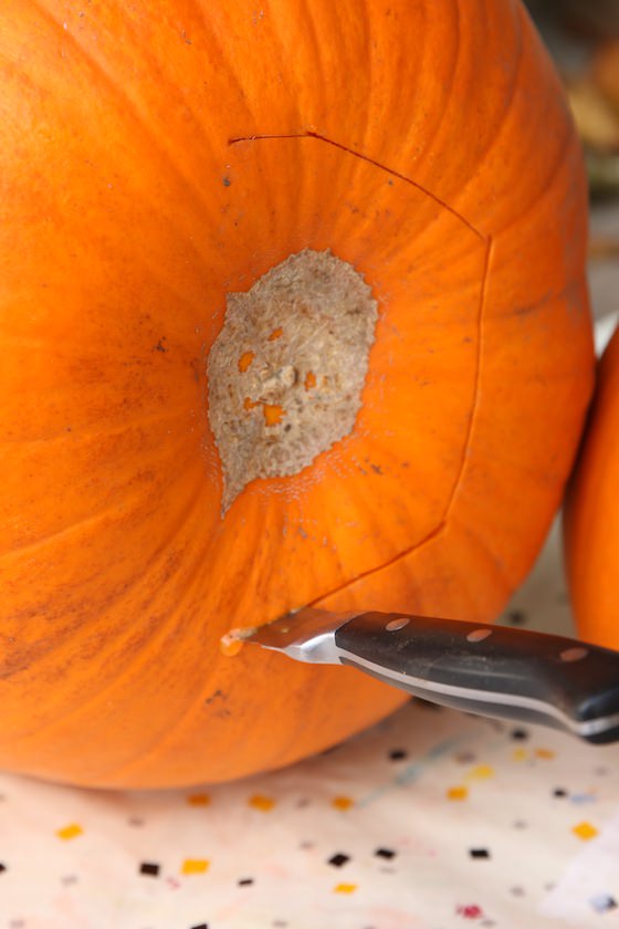 knife cutting into bottom of pumpkin