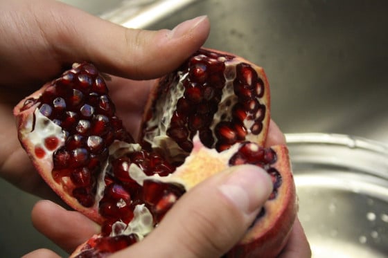 breaking open pomegranate with thumbs