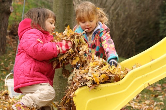 toddler and preschool girl putting leaves on slide