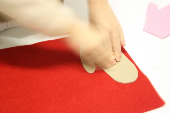 preschooler tracing cardboard mitten on red felt