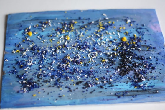 Blue canvas sprinkled with crayon shavings