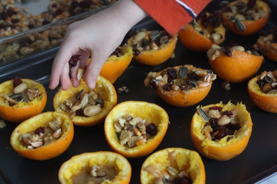 preschooler filling orange rinds with grains and nuts