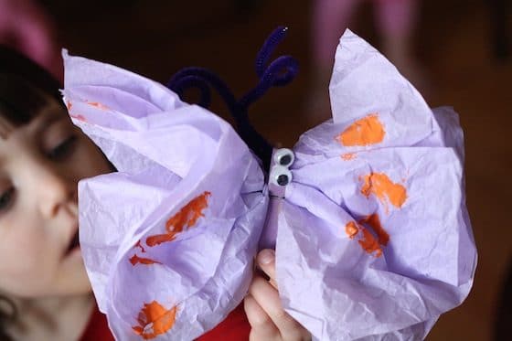 preschooler holding butterfly made from tissue paper and clothespin