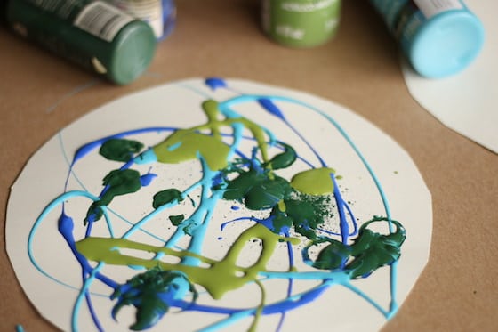 green and blue paint drizzled over white cardboard circle