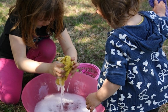  preschoolers washing facecloths in bowl of soapy water
