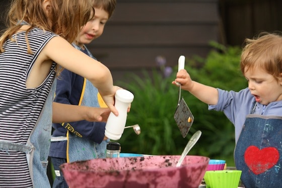 toddler and preschoolers mixing bowl of mud in backyard
