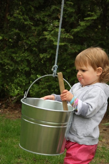 toddler filling bucket with wood
