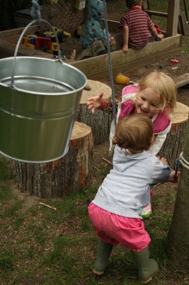 toddler and preschooler working together to raise bucket and rope contraption