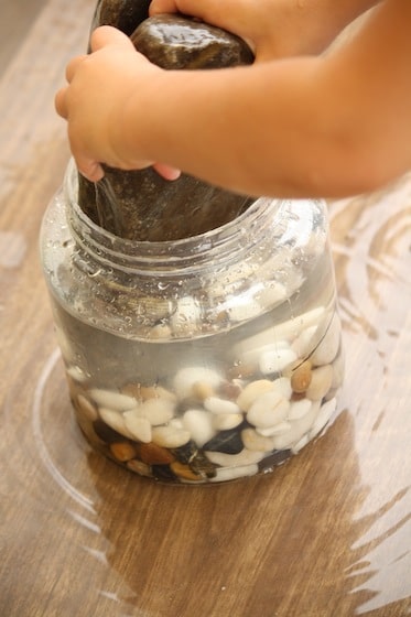 preschool water displacement experiment with stones and water in container