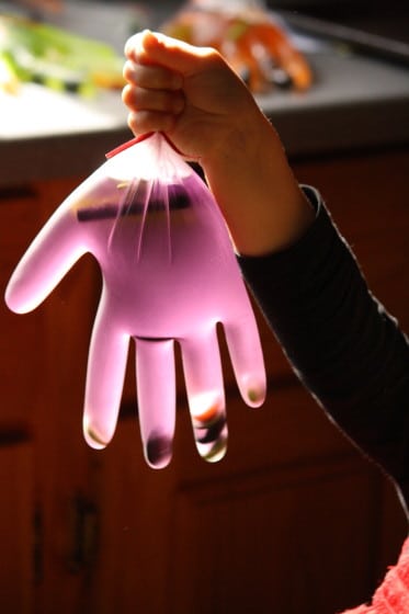 surgical glove filled with purple water and halloween items