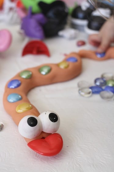 Homemade Playdough snake with potato head eyes and tongue, and glass beads along back.