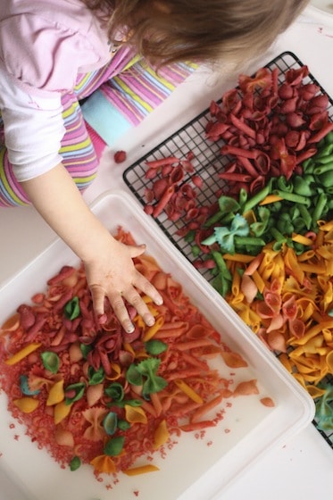 toddler playing with dyed pasta