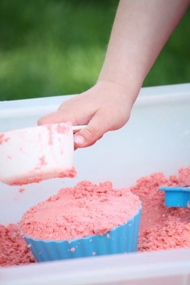 child scooping coloured cloud dough