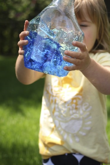 child shaking bottle of water and food colouring