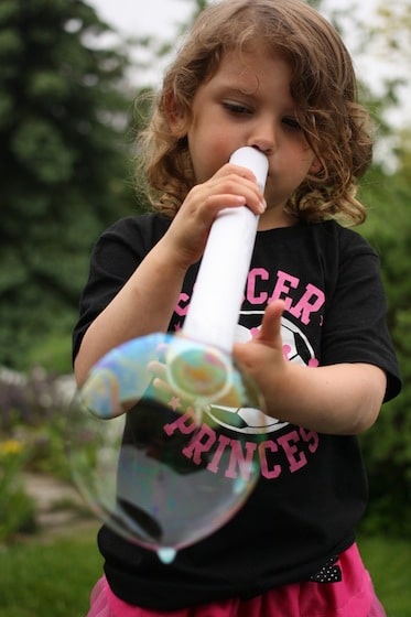child blowing bubble with cardboard tube
