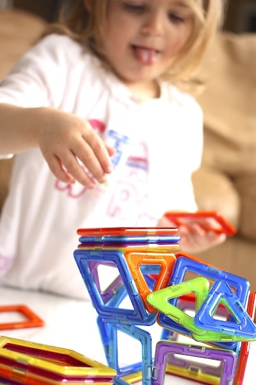 toddler building a 3 dimensional structure with Magformers