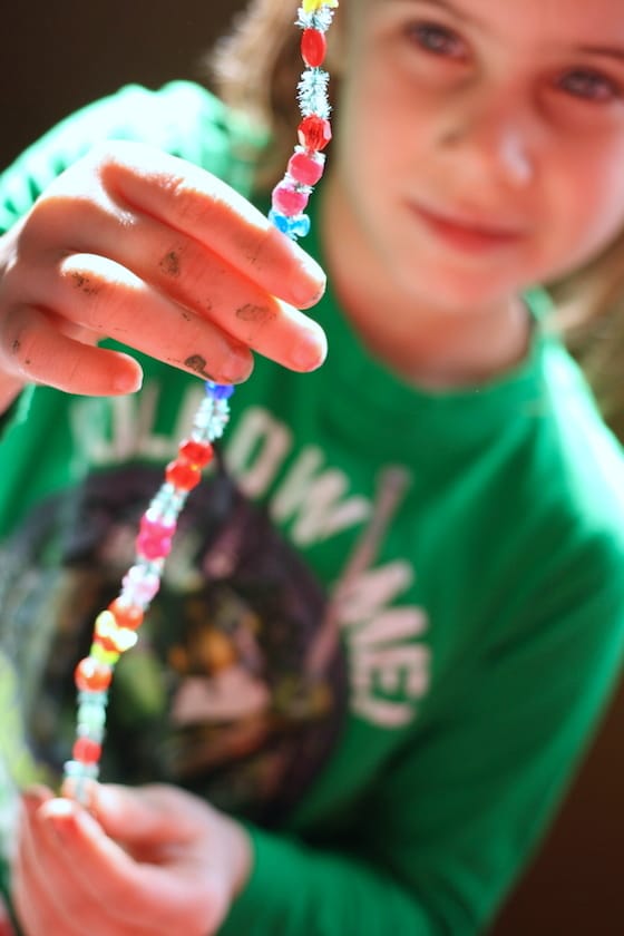 girl holding pipe cleaner threaded with beads