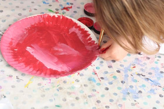 preschooler painting paper plate red