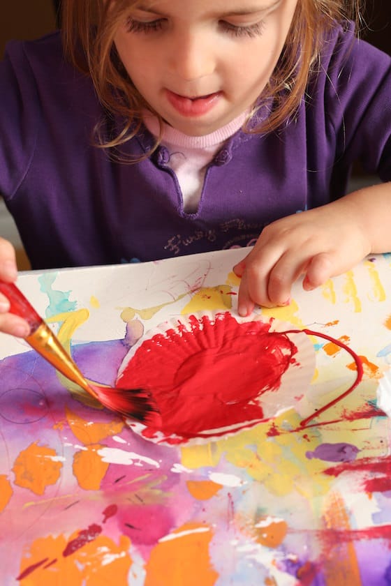 preschooler painting a cupcake liner