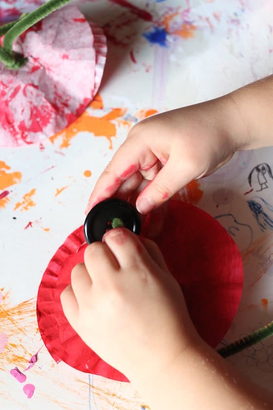 preschooler making a poppy with a cupcake liner and button