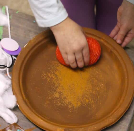 preschooler pouncing brown paint on a paper plate