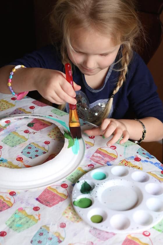 child painting paper plate green