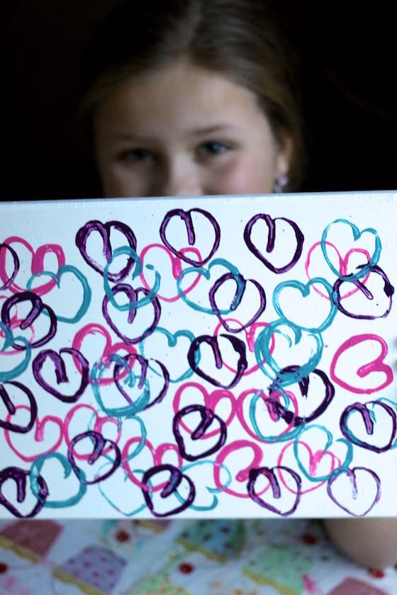 child holding cardboard roll heart art project
