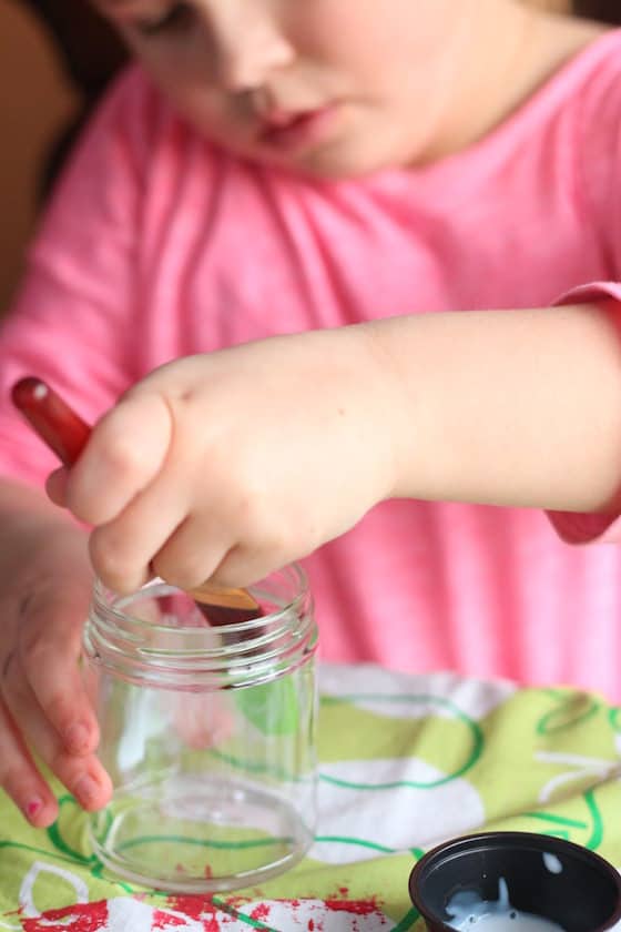 Child brushing glue inside glass jar