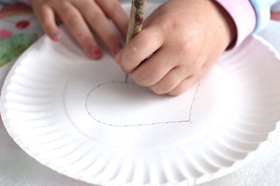 Poking holes in paper plate for kids beginner sewing project