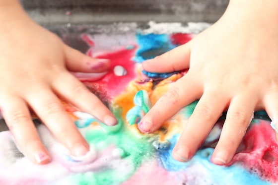 childs hands in baking soda, vinegar and food colouring