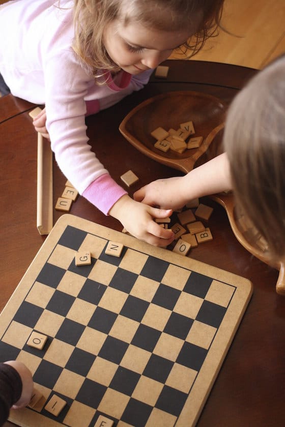 children placing scrabble letters on a checkerboard
