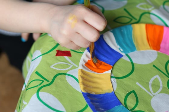 Child painting around the rim of a paper plate